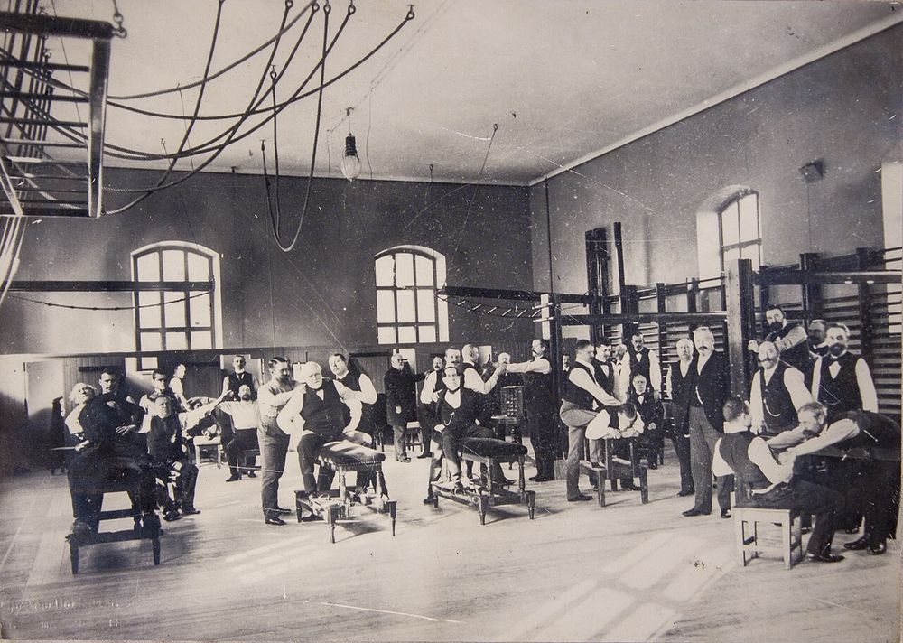 Grande salle de gymnastique avec chevaux d’arçons et suspensions au plafond, v. 1880